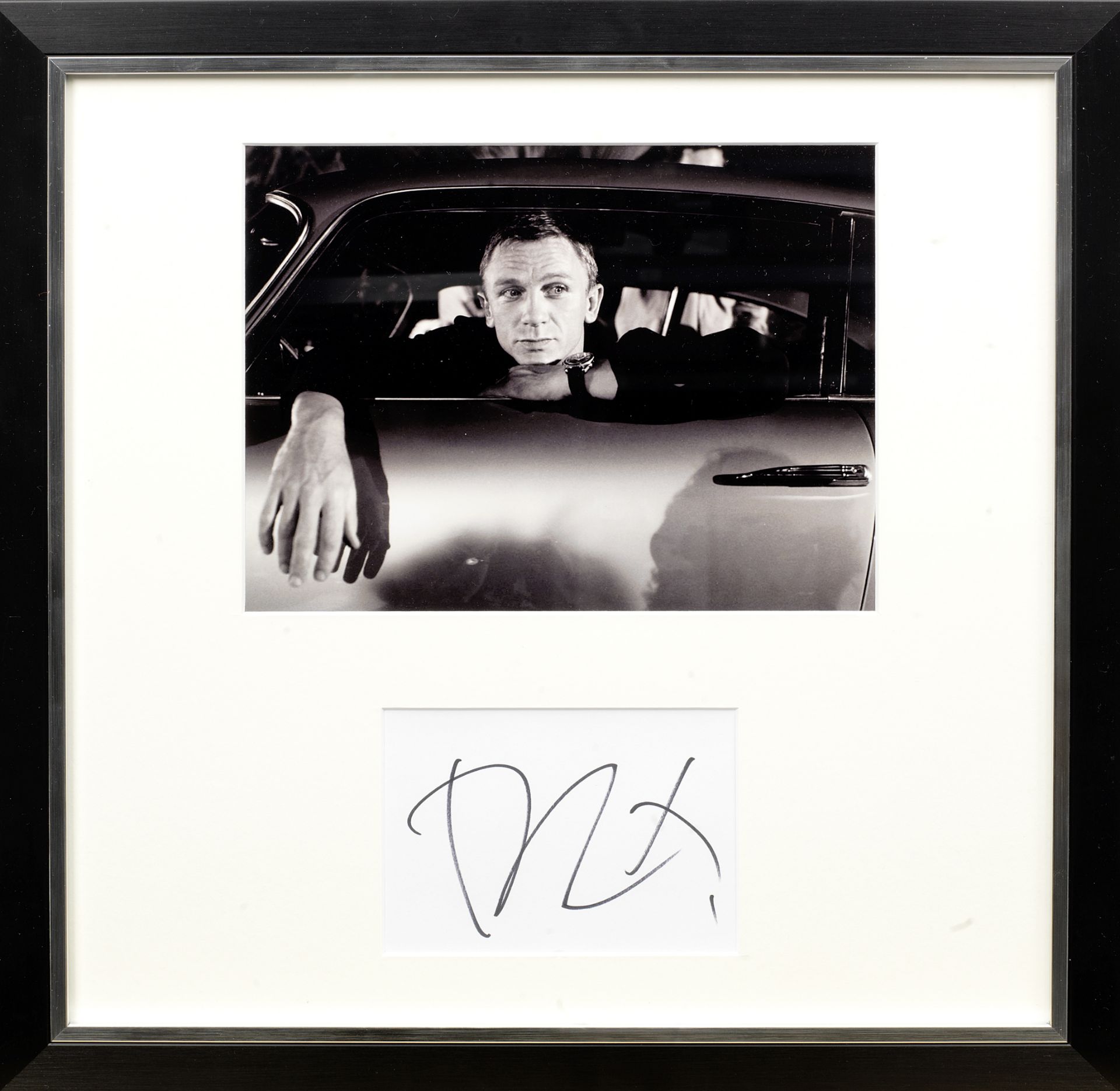 A framed photograph with signature of Daniel Craig with the James Bond Aston Martin DB5,