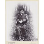 A photographic portrait of Nasr al-din Shah Qajar (reg. 1848-96), depicted seated outdoors in woo...