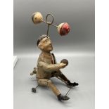 Antique tinplate clockwork man seated with clapping bells. In a working condition.