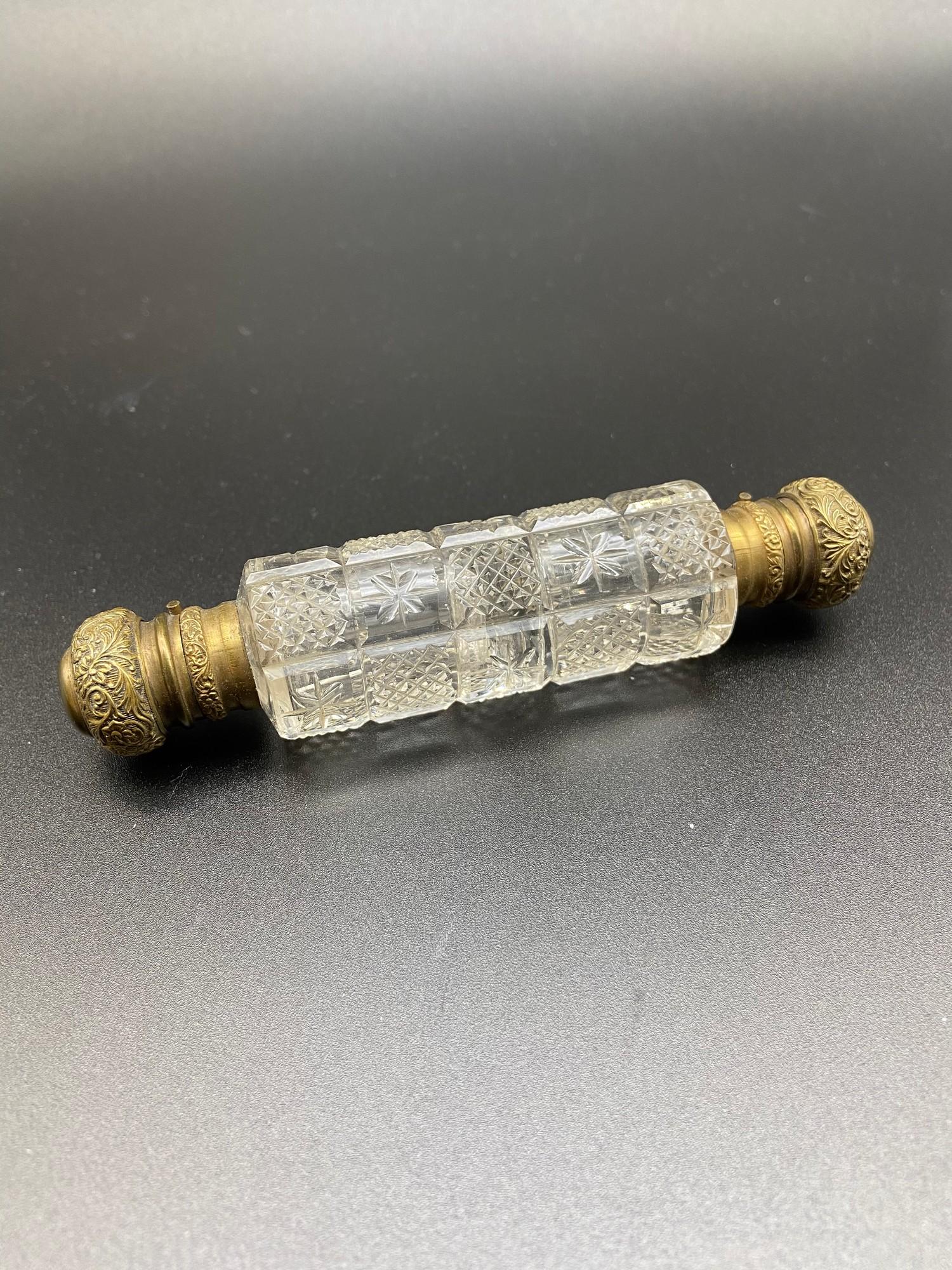 Antique double ended perfume bottle. Designed with two gilt metal tops and cut glass body. Comes