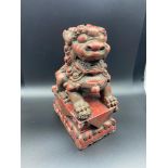 An 18TH/19th century hand carved wooden foo dog sculpture finished with a red lacquered paint with a