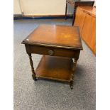 A 1950's two tier side table designed with a single drawer and castor feet supports.