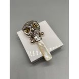A Sterling silver babies rattle in the form of an owls head. Finished with a mother or pearl handle.