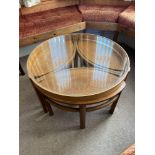 A Retro mid century teak and glass round coffee table designed with three under side tables.