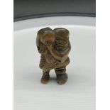 A Japanese hand carved netsuke of a gentleman carrying a bag. Signed.