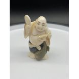 A Japanese Meiji period ivory carved netsuke of a laughing buddha holding a rat. [7cm in height]