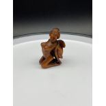 A Japanese hand carved netsuke of a semi nude geisha woman. Signed to the bottom of her robe.