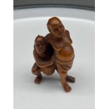 A Japanese hand carved netsuke of two men wrestling. Signed. [5cm in height]