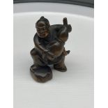 A Japanese hand carved netsuke of a gentleman carrying a flagon of wine. Signed.