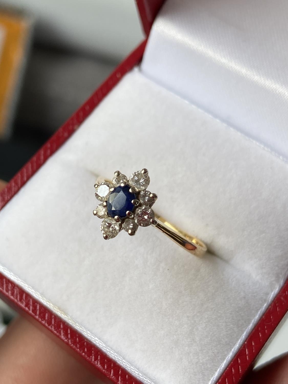 A ladies gold [possibly 18ct] ring set with a single sapphire & diamond ring, surrounded by 8