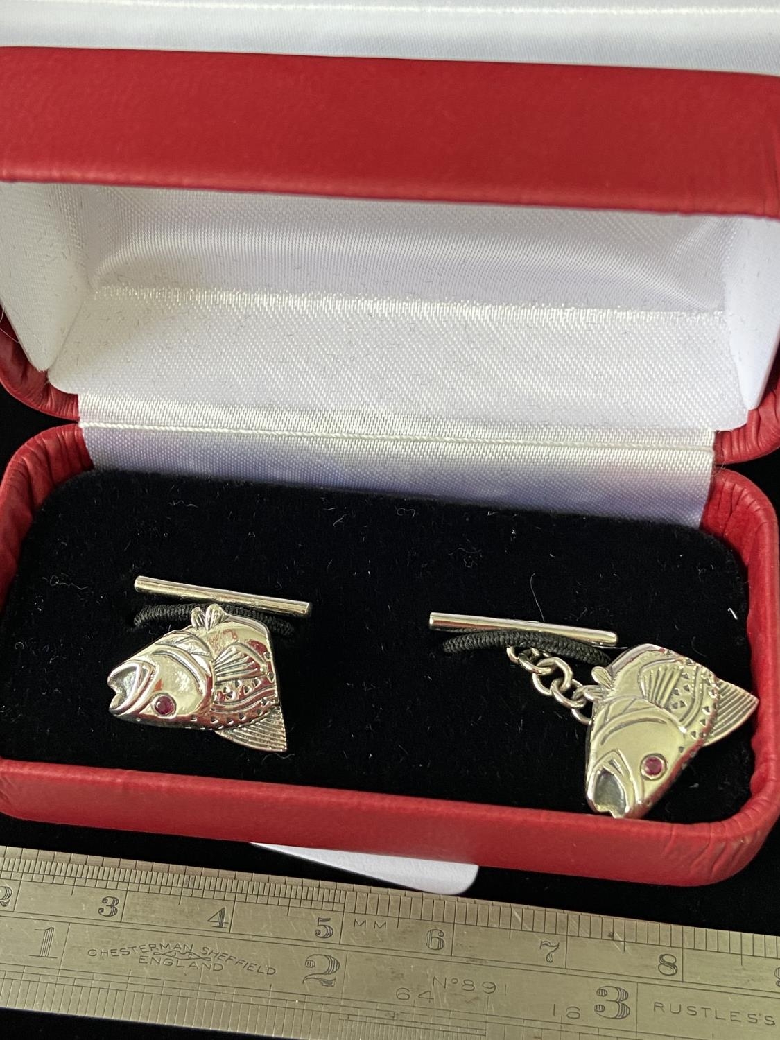 A Pair of silver salmon headed cufflinks with ruby eyes.