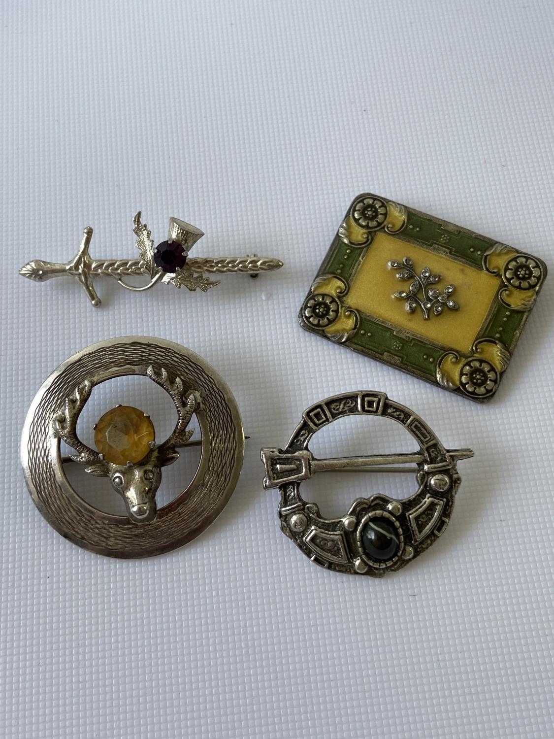 A Glasgow silver stag & citrine brooch, Sterling silver sword brooch, pewter Celtic brooch and a