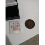 A TWO HEADED PENNY GEORGE V COIN WITH SMALL LEAFLET.