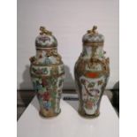 A LOT OF TWO ANTIQUE CHINESE FAMILLE ROSE HAND PAINTED URNS WITH LIDS. DESIGNED WITH RAISED RELIEF