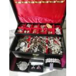 A Jewellery box containing a quantity of costume jewellery to include brooches, necklaces,