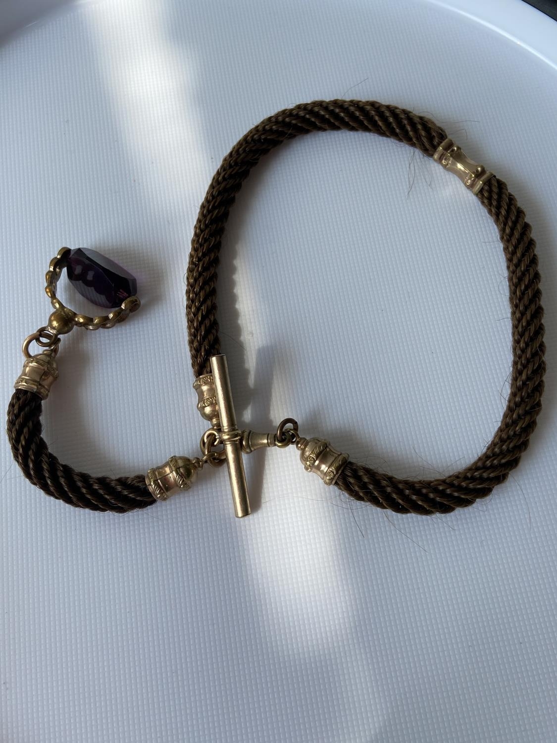 A 19th century albert chain made from braided hair, gilt metal attachments and amethyst & gilt metal