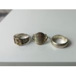 Three various silver gent's rings to include buckle ring, wedding band and George and the dragon