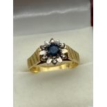 A Ladies 18ct gold single sapphire and 6 small diamond stone ring. Designed like a flower. [5.