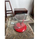 A comtemporary style table designed with red base, chrome & red supports and a glass circular top