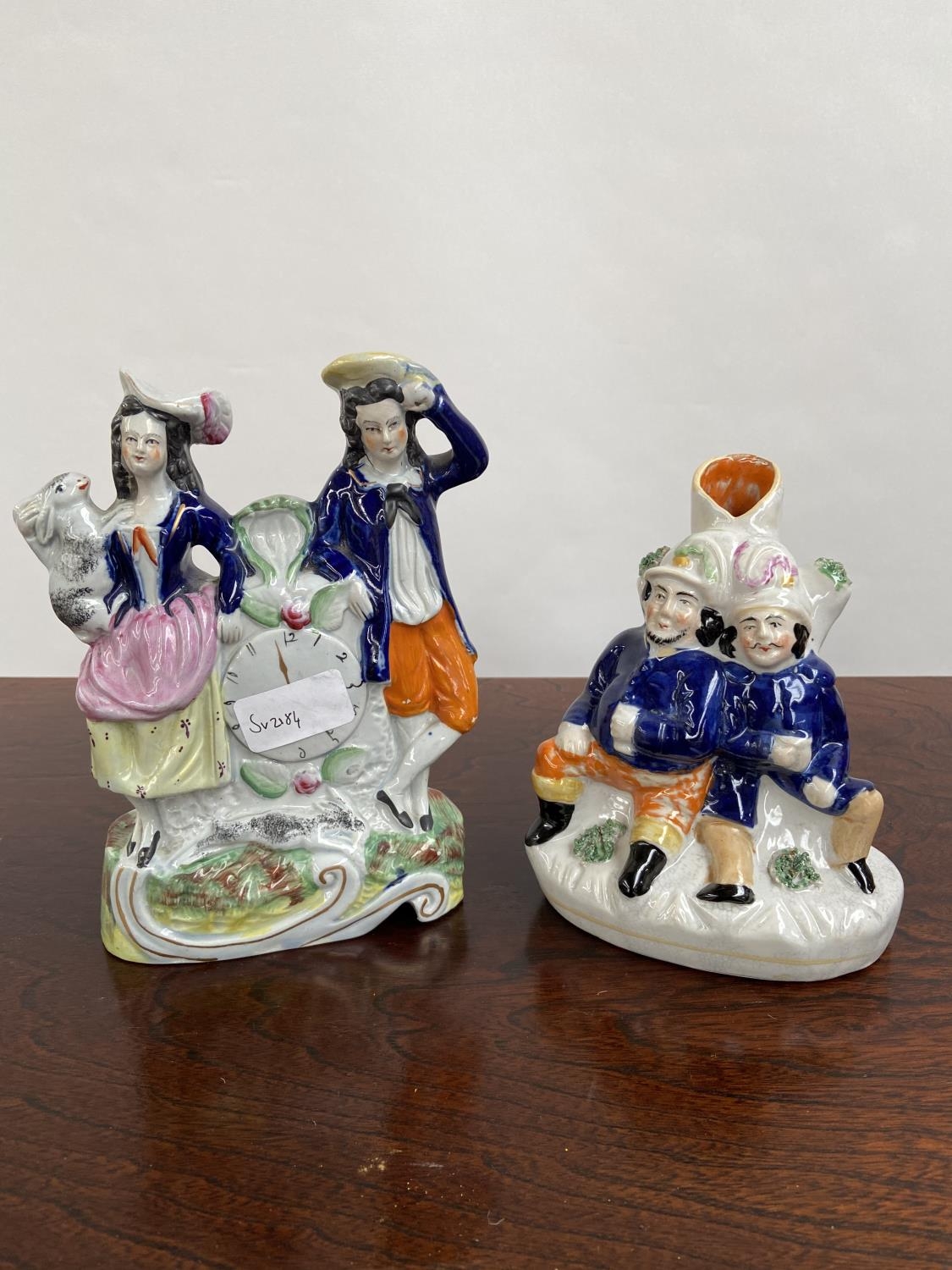 Two various antique Staffordshire figurines to include clock design couple figurine and two gents