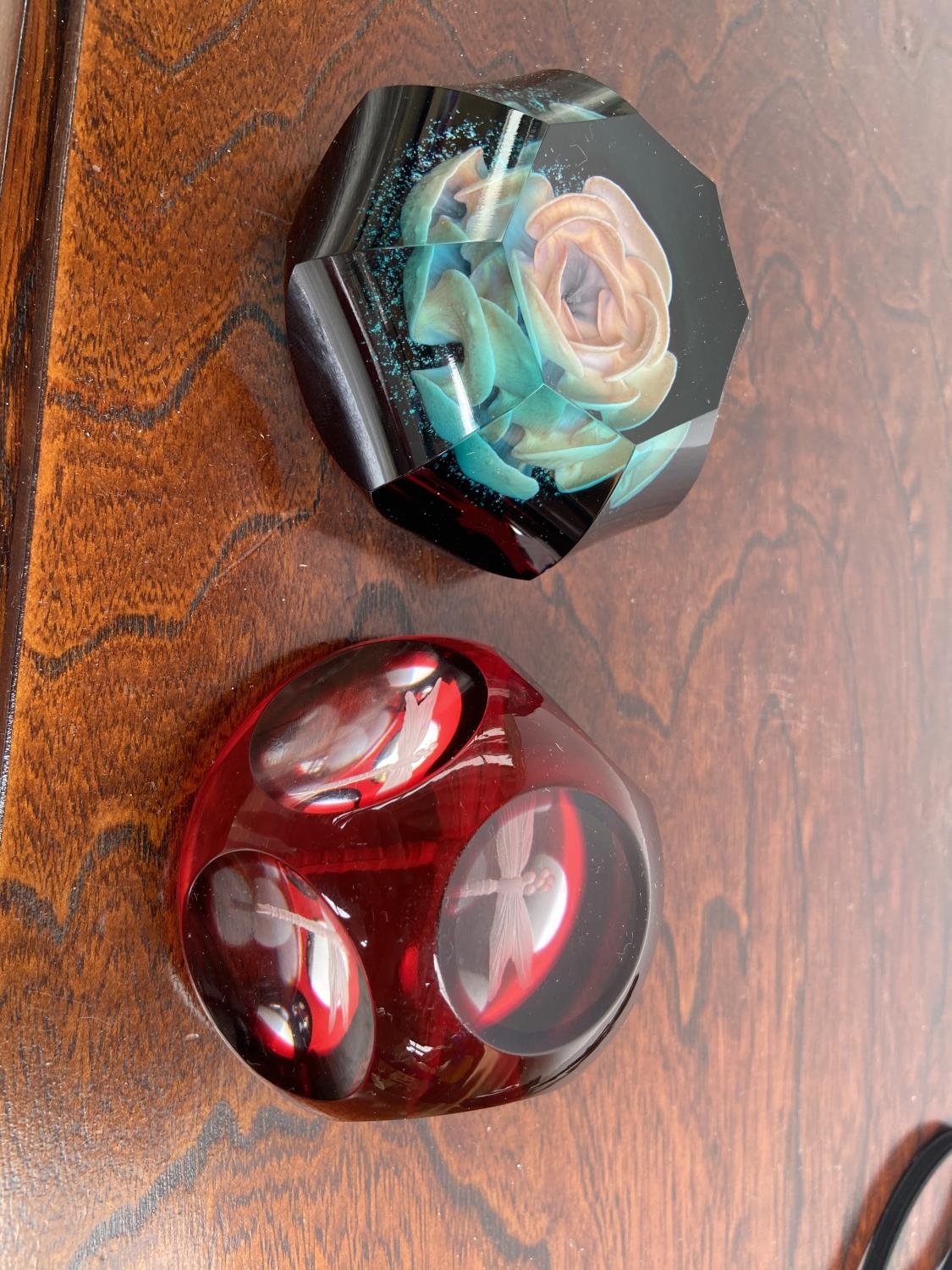 Two unusual style paperweights. A Pink Rose in a facet cut blue glass and an etched dragon fly red