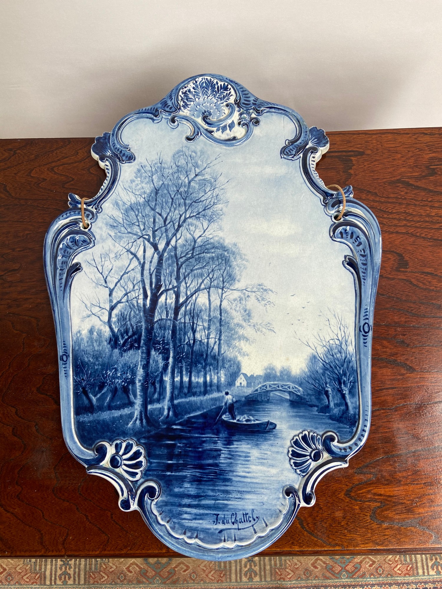 A Large Delft blue and white wall plaque depicting man rowing down a canal scene. Signed J. Du