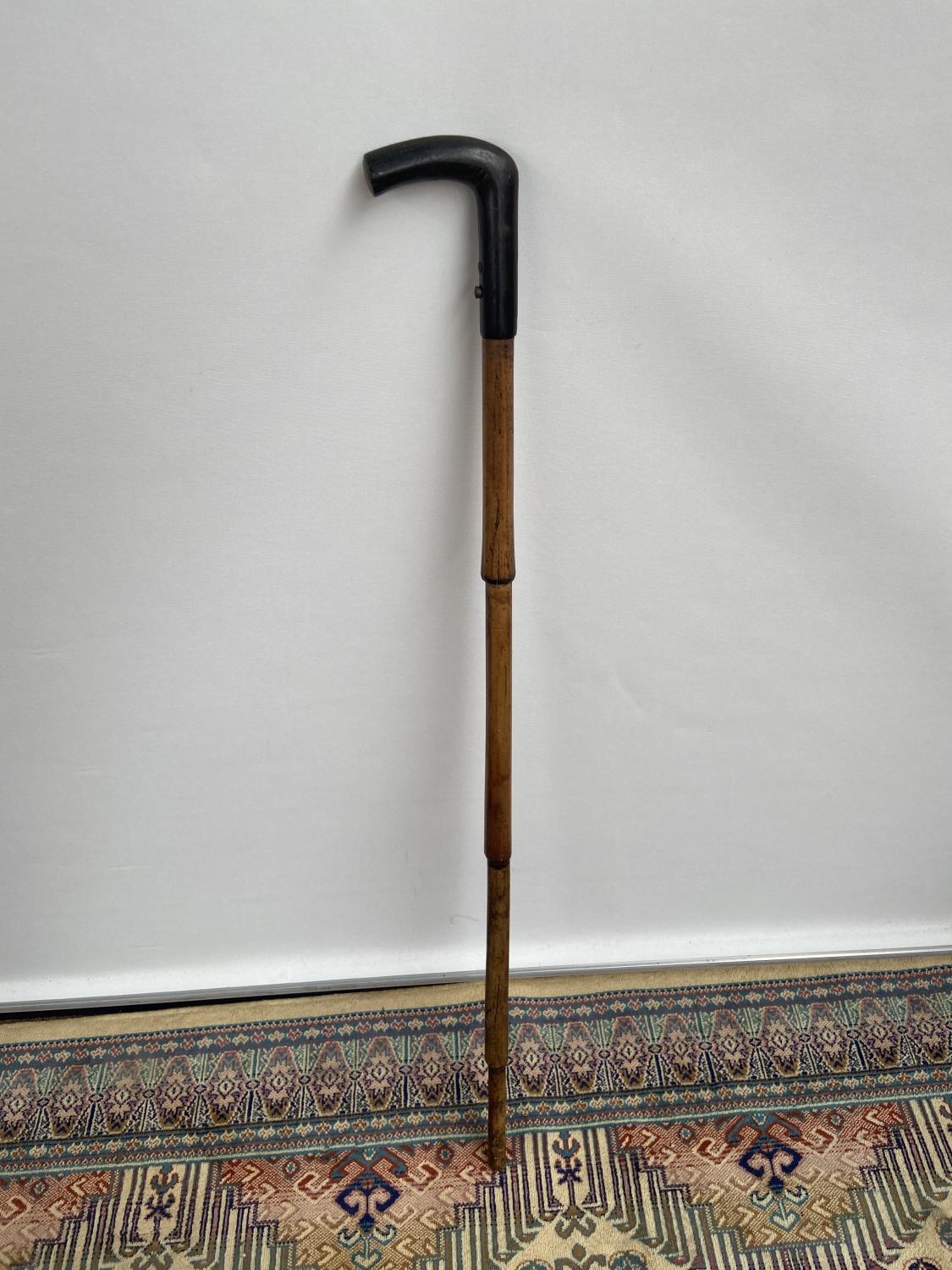 An antique walking cane pistol, designed with a bone handle and bamboo shaft [length, 90cm]