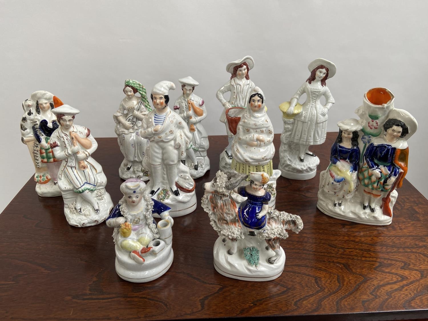 A Collection of antique Staffordshire figurines to include young girl sat upon a rams back, Asian