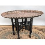 A 19th century middle eastern copper tea table, with an oval shape and detailed with engravings to