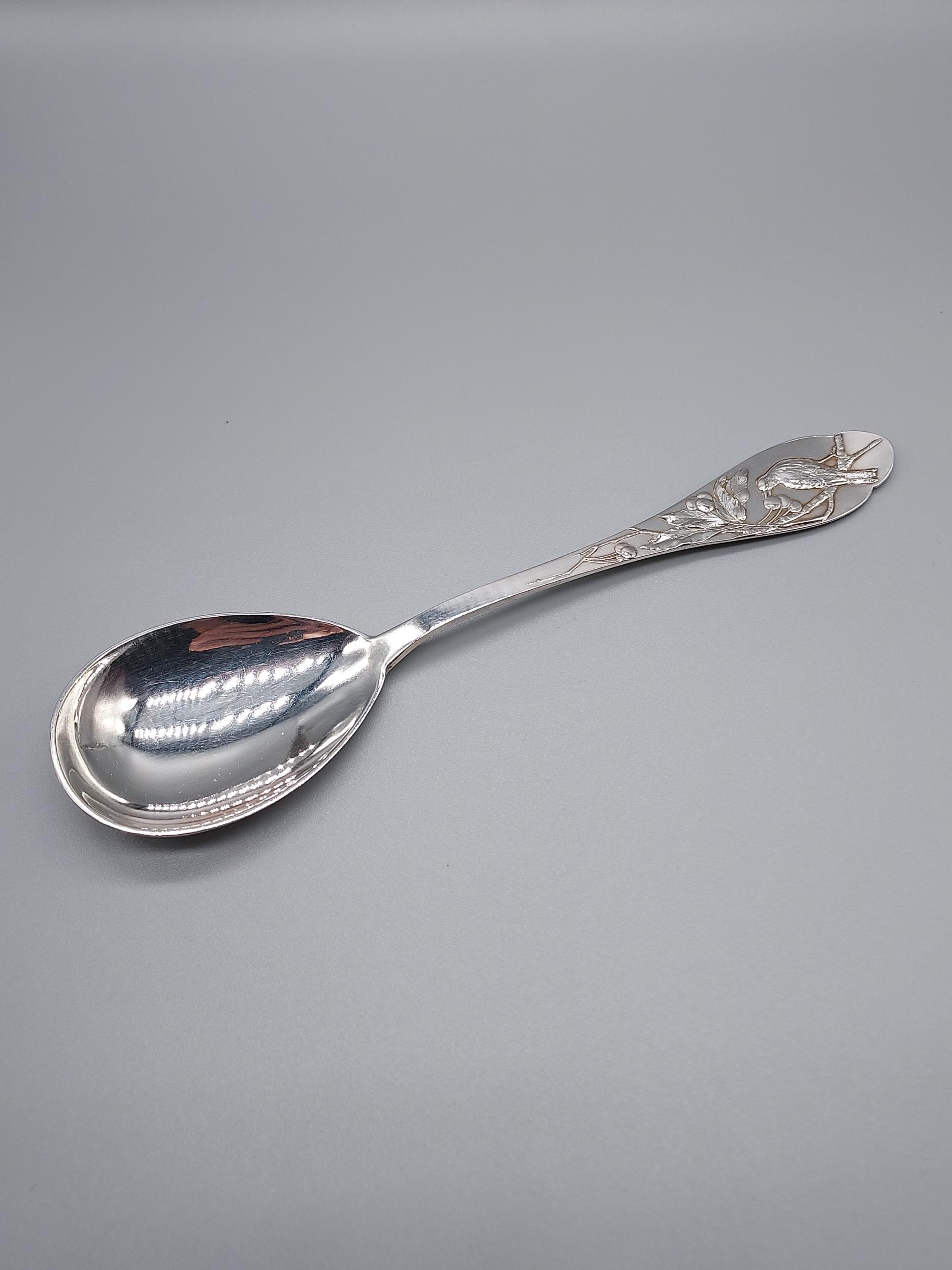 A German 800 Silver marked desert spoon, Designed with a raised relief bird eating berries. [19.