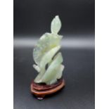 A Chinese hand carved jade sculpture depicting a koi carp and flower.Sat on a wooden base [12.5cm in