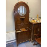An Art Deco dark oak hall stand, designed with a centre mirror and off set by 6 metal coat