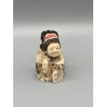 A Japanese hand carved bone netsuke of a women in an ornate robe. Signed. [5cm in height]