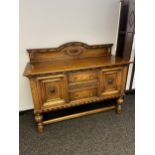 An antique solid oak Art Deco sideboard designed on bulbous carved leg supports and decorative