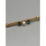 An Antique 9ct gold bar brooch set with a single pearl off set by a single black opal to either