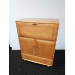 An Ercol light elm wood secretaire unit. Consists of two doors, one drawer and pull down writing