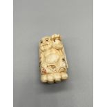 An early 20th century Japanese hand carved bone netsuke of a sitting laughing buddha held within a