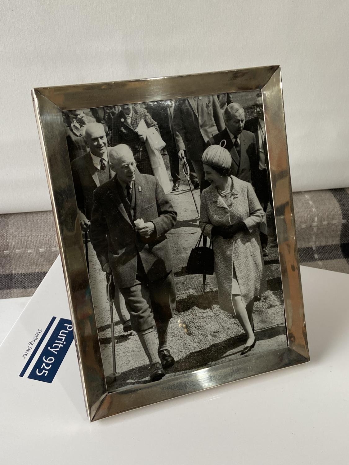 An original photograph of an elderly gentleman walking with Queen Elizabeth II. Fitted within a