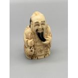 An early 20th century hand carved bone Japanese netsuke of an elderly gentleman stroking his beard