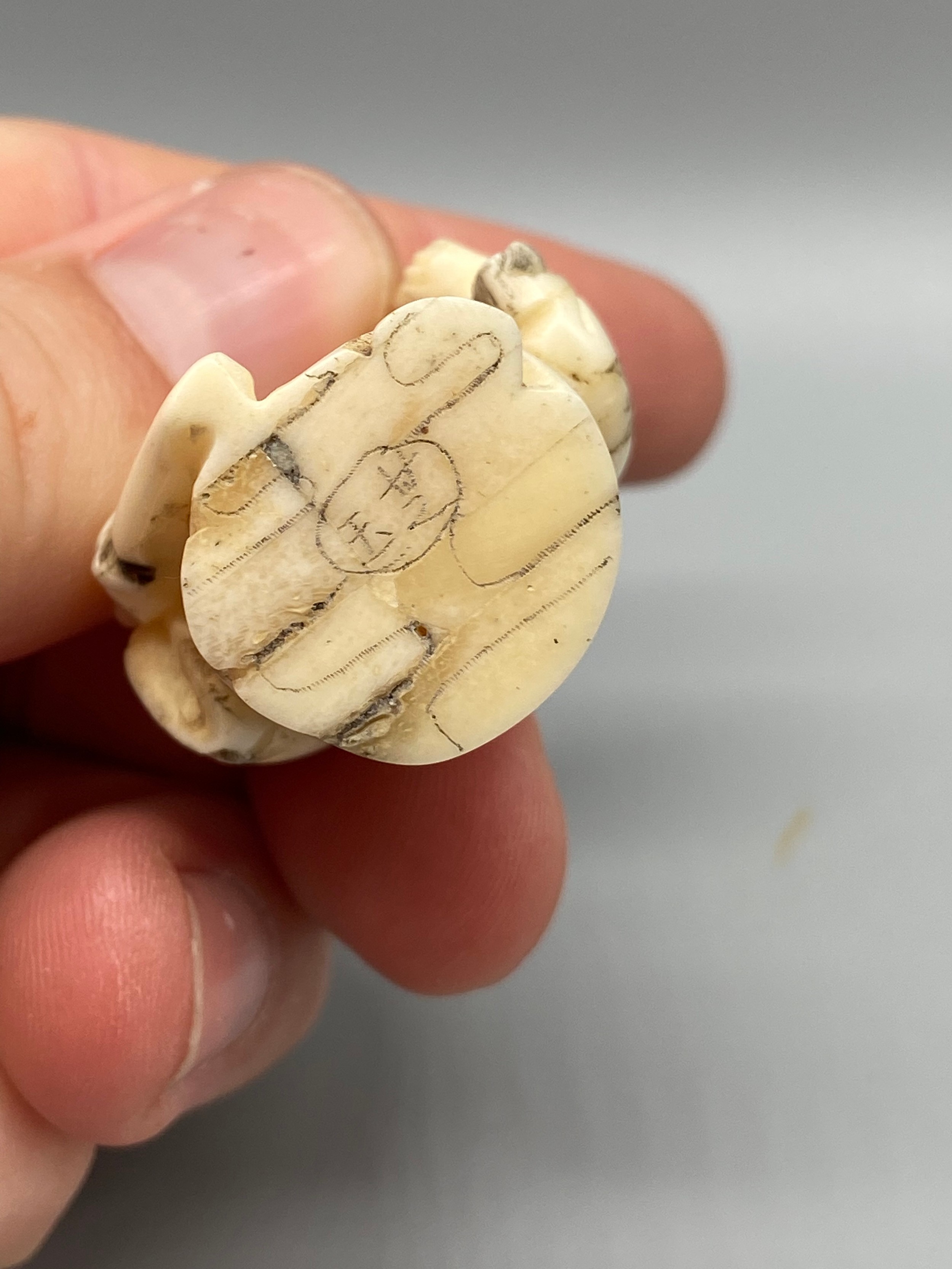 An early 20th century Japanese hand carved bone netsuke of a cloaked gentleman holding a sword and - Image 4 of 5