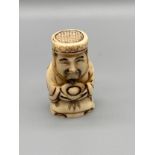 A Japanese hand carved bone netsuke of an elderly gentleman holding a token. Signed. [5.2cm in