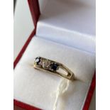 A 9ct gold sapphire & diamond ring set with a single bright white diamond [3mm] off set by two