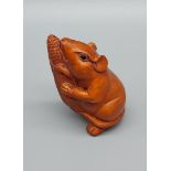 A Japanese hand carved netsuke of a mouse holding a corn. Signed. [4.5cm in height]