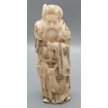 A highly detailed Japanese hand carved bone figure of an emperor holding a dragon design sword,