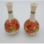 A Pair of Moorcroft Hibiscus design bud vases. Showing original label and signed to the base [21cm