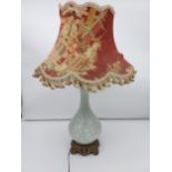 A Chinese Celadon floral design table lamp sat upon a gilt metal base. Comes with a Chinese silk