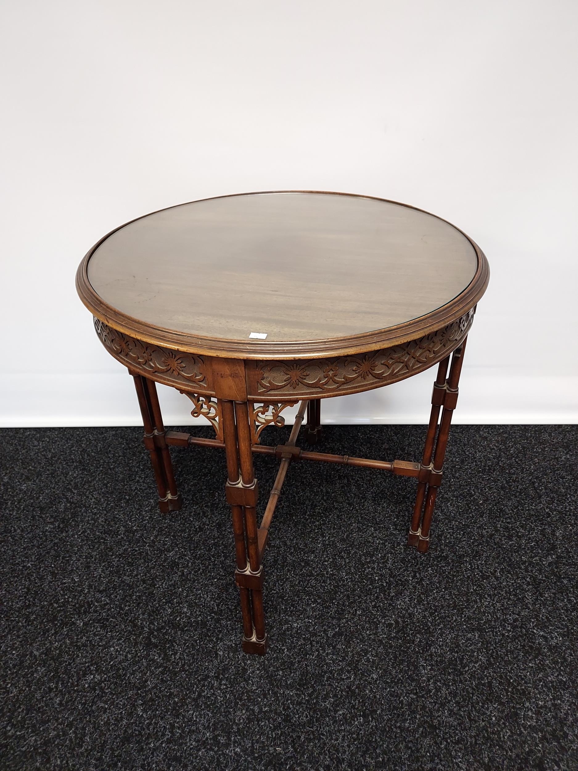 A 19th century barrel window table with glass top above a carved frieze,