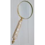 A large hand held magnifying glass with mother of pearl handle