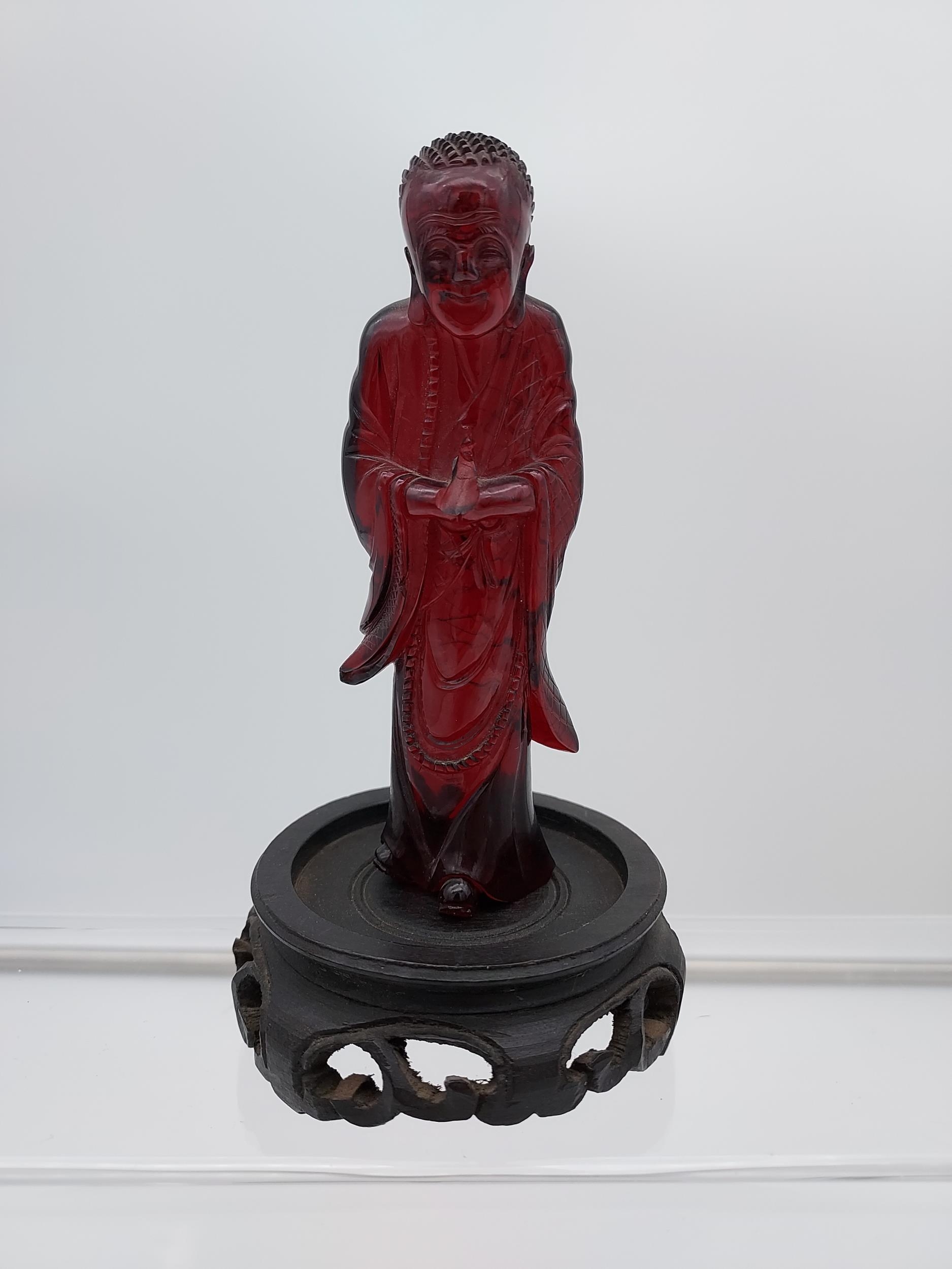 A 19TH Century Chinese hand carved Cherry amber buddha figurine with a hand carved wooden base. [