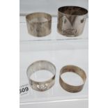 Four various silver marked napkin rings together with an ornate Birmingham silver menu holder. [